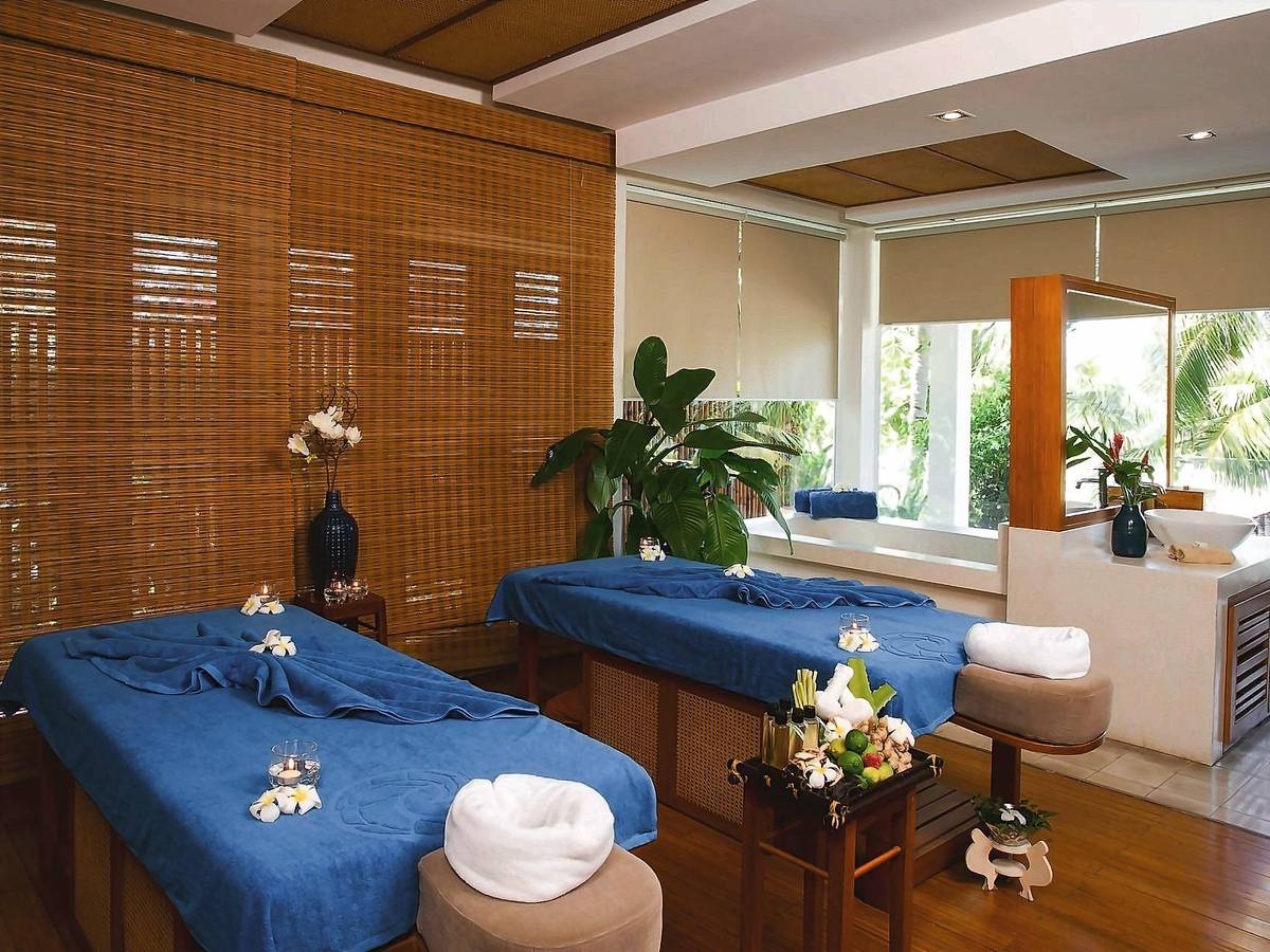 Spa room with two massage beds dressed in blue, timber screens and garden light