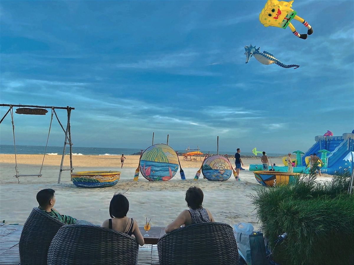 Guests watching kites from swing seats on the sand, with painted basket boats nearby