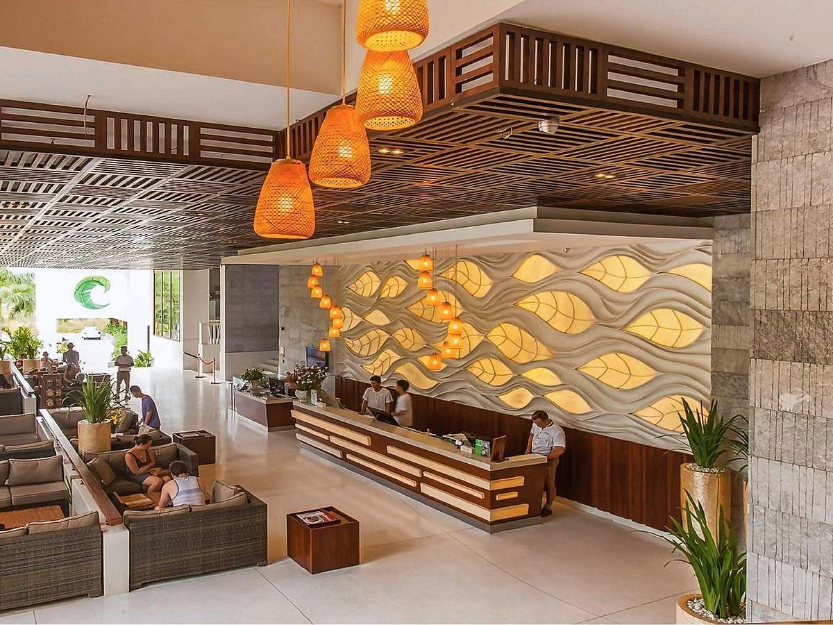 Reception desk with a lit leaf-pattern wall and lounge chairs in the lobby