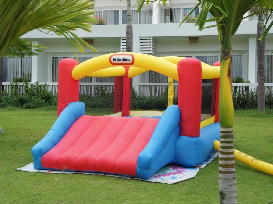 Colourful inflatable bouncy castle on a green lawn in front of resort buildings