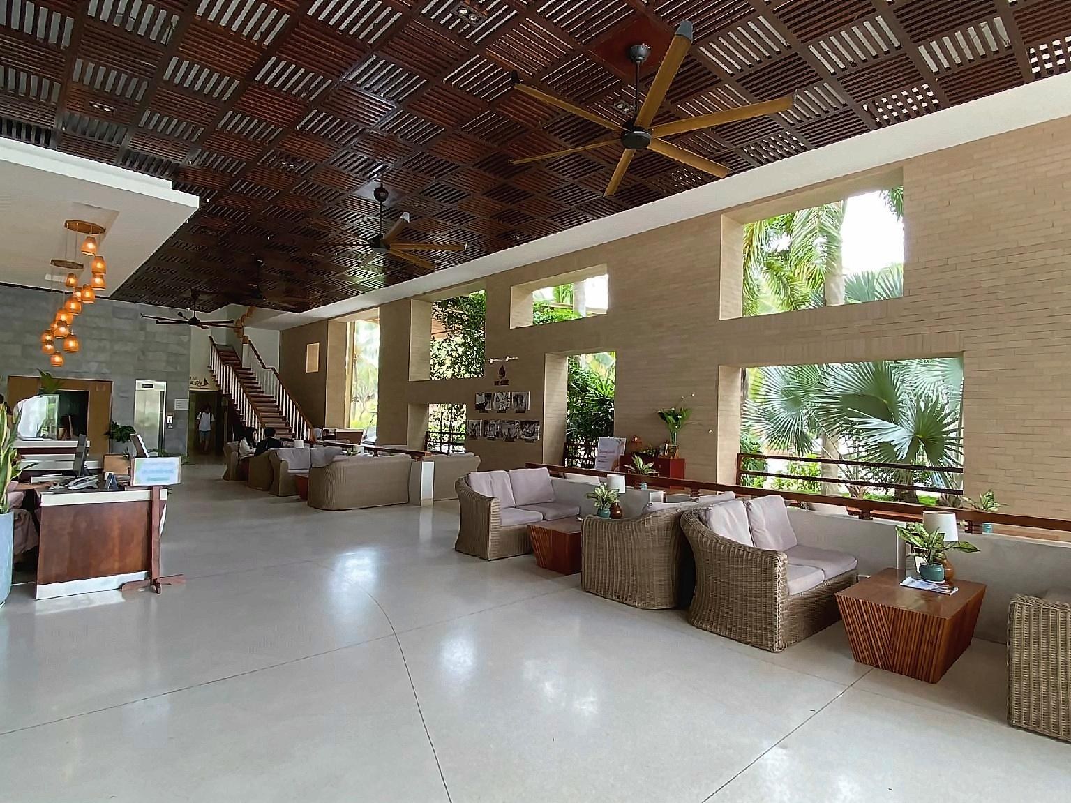 Open-sided lobby with low sofas, a timber slatted ceiling and garden views