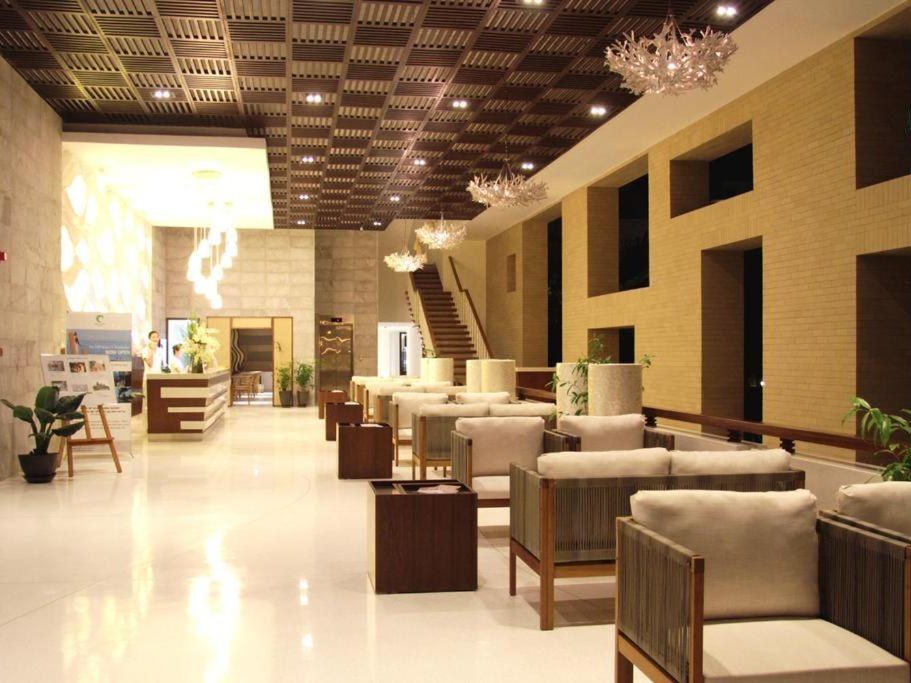 Lobby lounge with cream armchairs, a stone wall and a coffered timber ceiling