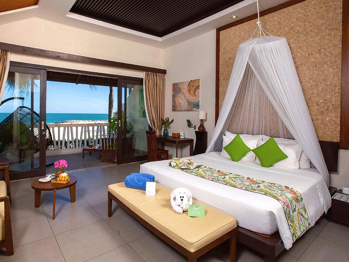 Bungalow bedroom with a canopy bed, dark wood ceiling and a terrace looking to the sea