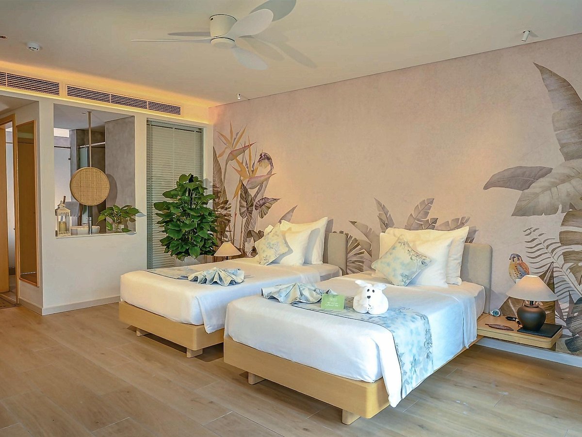 Light room with twin beds, a leaf-print wall and a small sitting corner