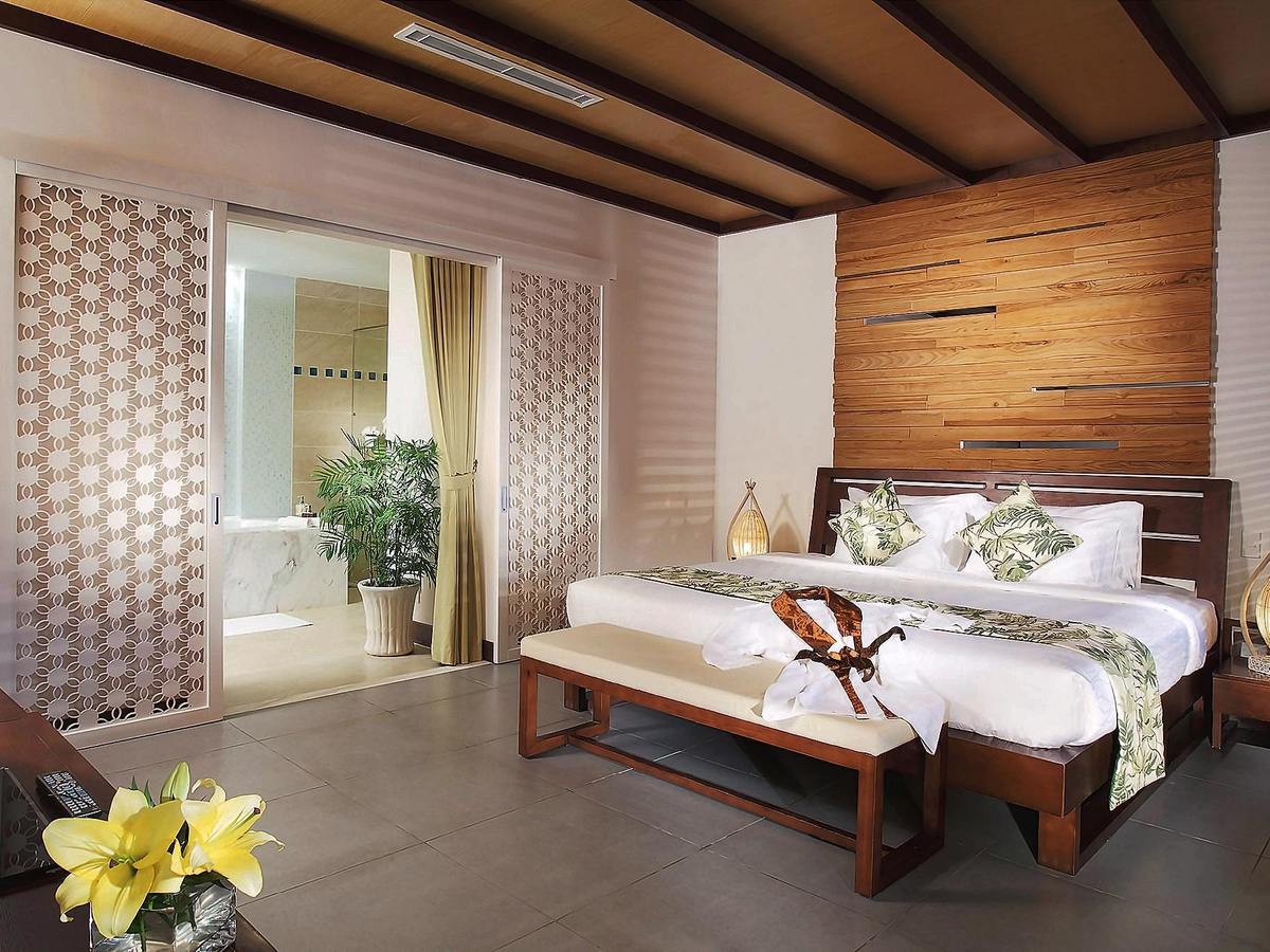 Bedroom with a timber-slatted wall, white bedding and a glass door to a bathroom