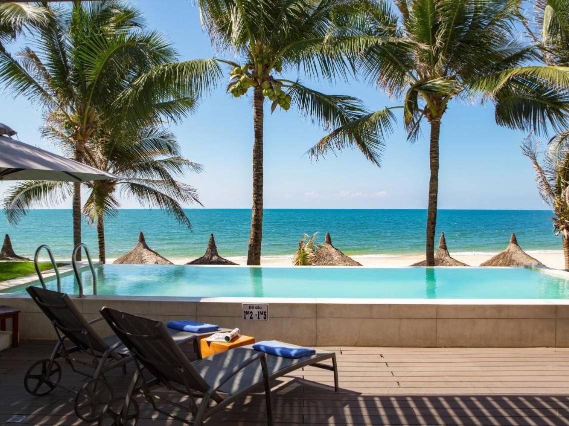 Beachfront villa terrace with a private infinity pool, loungers and palm trees